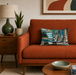 Orange sofa with a decorative pillow in a living room setting.