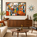 A large abstract geometric canvas print by Portland Oregon artist Leah Nadeau, with warm orange, brown, teal, and cream tones hangs on a beige wall above a mid-century modern wooden credenza in a styled living room.
