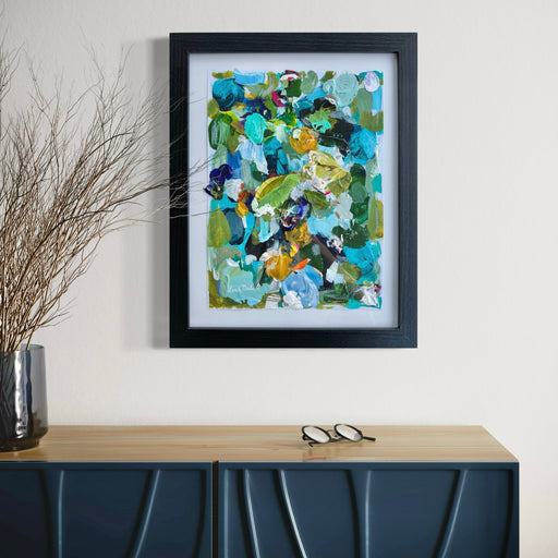 Framed abstract art piece on a wall above a blue cabinet.