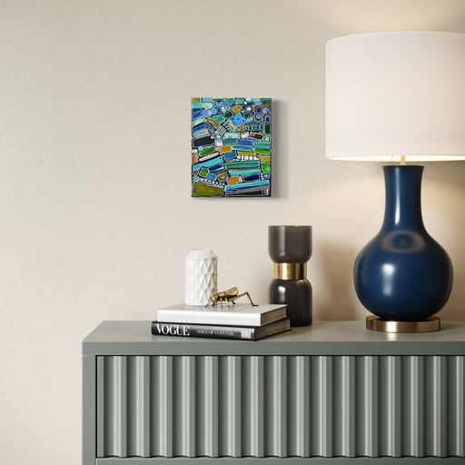 Gray console table with decorative items including a blue lamp, books, and a small sculpture, with a colorful abstract painting on the wall.